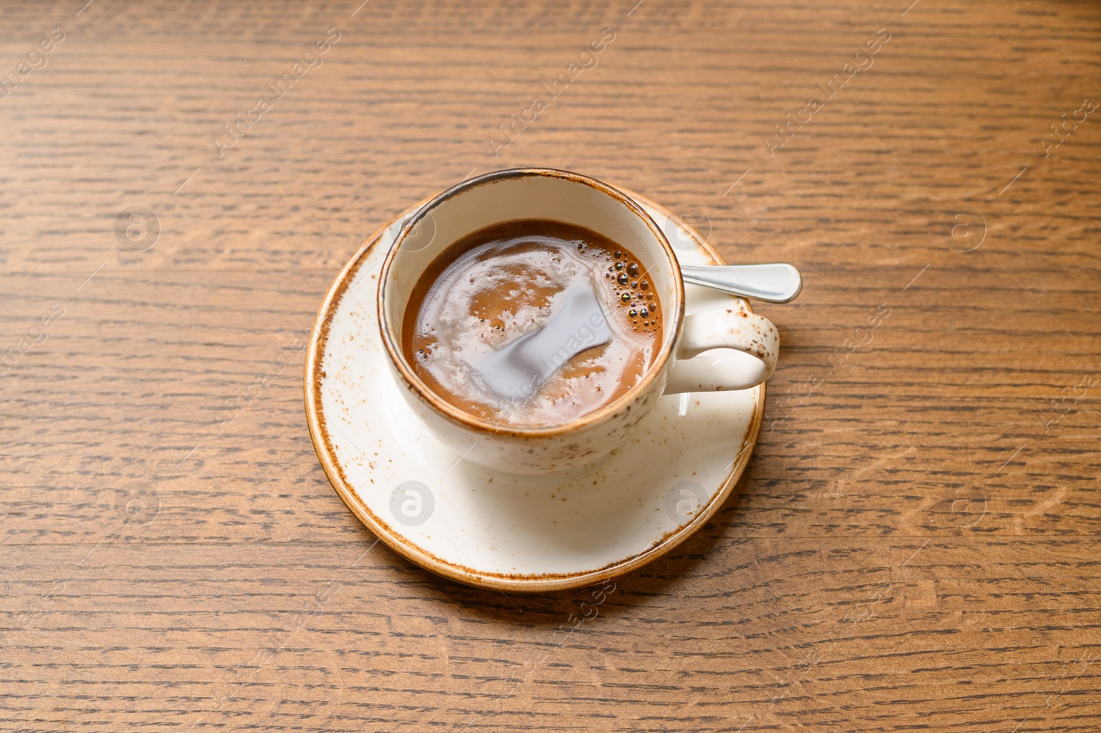 Photo of Cup of aromatic coffee on wooden table, above view