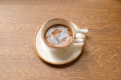 Photo of Cup of aromatic coffee on wooden table, above view
