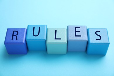 Photo of Word Rules made of wooden cubes with letters on light blue background, above view
