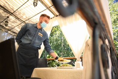 Waiter serving food in restaurant. Catering during coronavirus quarantine