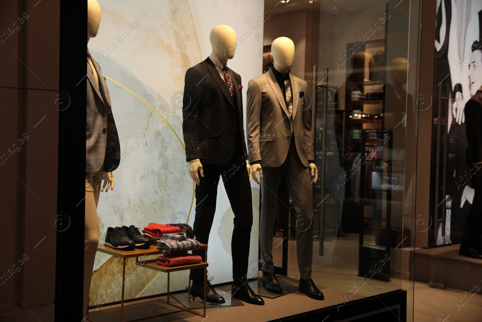 Photo of Beautiful suits on mannequins in showcases of fashion store