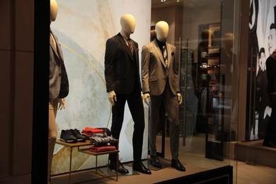 Photo of Beautiful suits on mannequins in showcases of fashion store