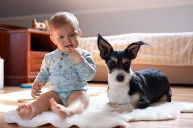 Photo of Adorable baby and cute dog on faux fur rug at home