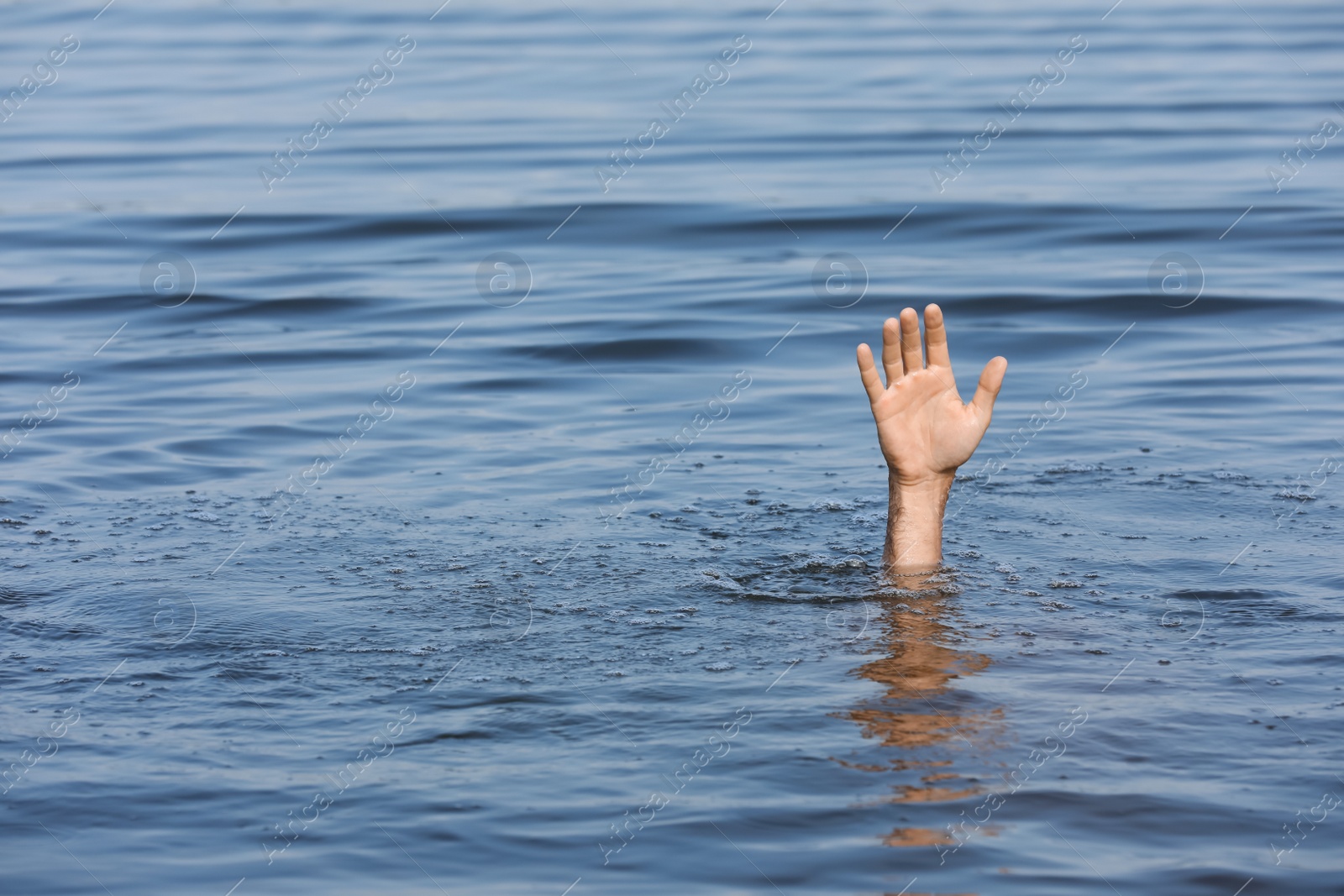 Photo of Drowning man reaching for help in sea, closeup