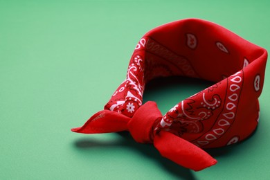 Tied red bandana with paisley pattern on light green background, closeup