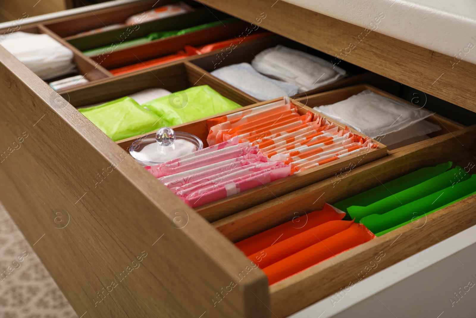 Photo of Storage of different feminine hygiene products in wooden drawer, closeup