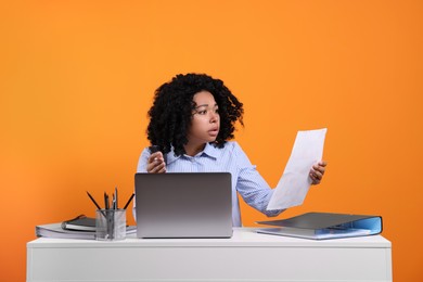 Photo of Stressful deadline. Woman checking document at white desk against orange background
