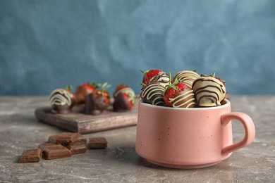 Photo of Cup with chocolate covered strawberries on table