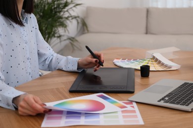 Photo of Professional designer with graphic tablet at wooden table, closeup