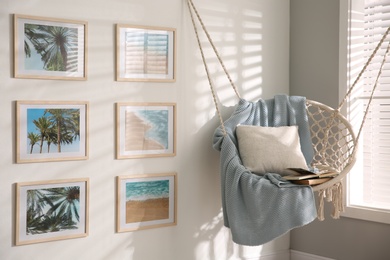 Photo of Different pictures on wall and hanging chair in room. Artworks in interior design