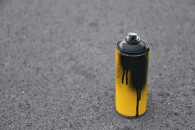 Photo of Used can of spray paint on asphalt. Space for text