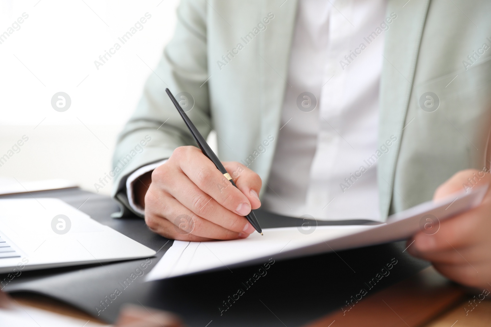 Photo of Male notary signing document at table in office, closeup