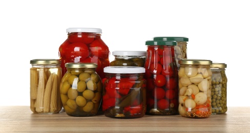Photo of Jars of pickled vegetables on wooden table
