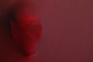 Photo of Silhouette of creepy ghost with skull behind cloth, space for text. Color toned