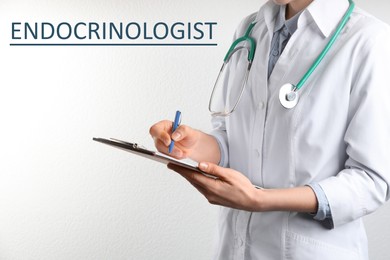 Endocrinologist with stethoscope, clipboard and pen near white wall, closeup