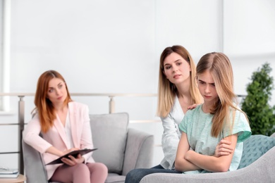 Photo of Young female psychologist working with teenage girl and her mother in office