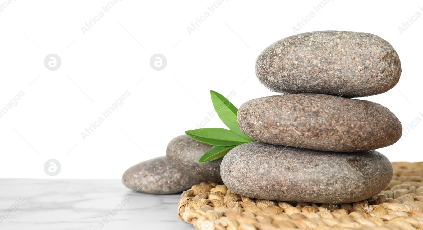 Photo of Spa stones with green branch on table against white background. Space for text