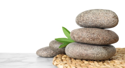 Photo of Spa stones with green branch on table against white background. Space for text