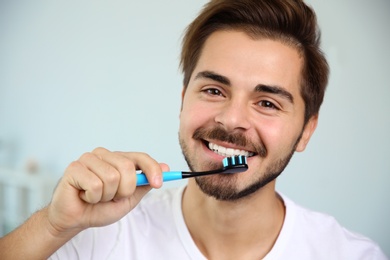 Photo of Portrait of young man with toothbrush on blurred background