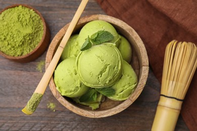 Photo of Tasty matcha ice cream, bamboo spoon with powder and whisk on wooden table, flat lay