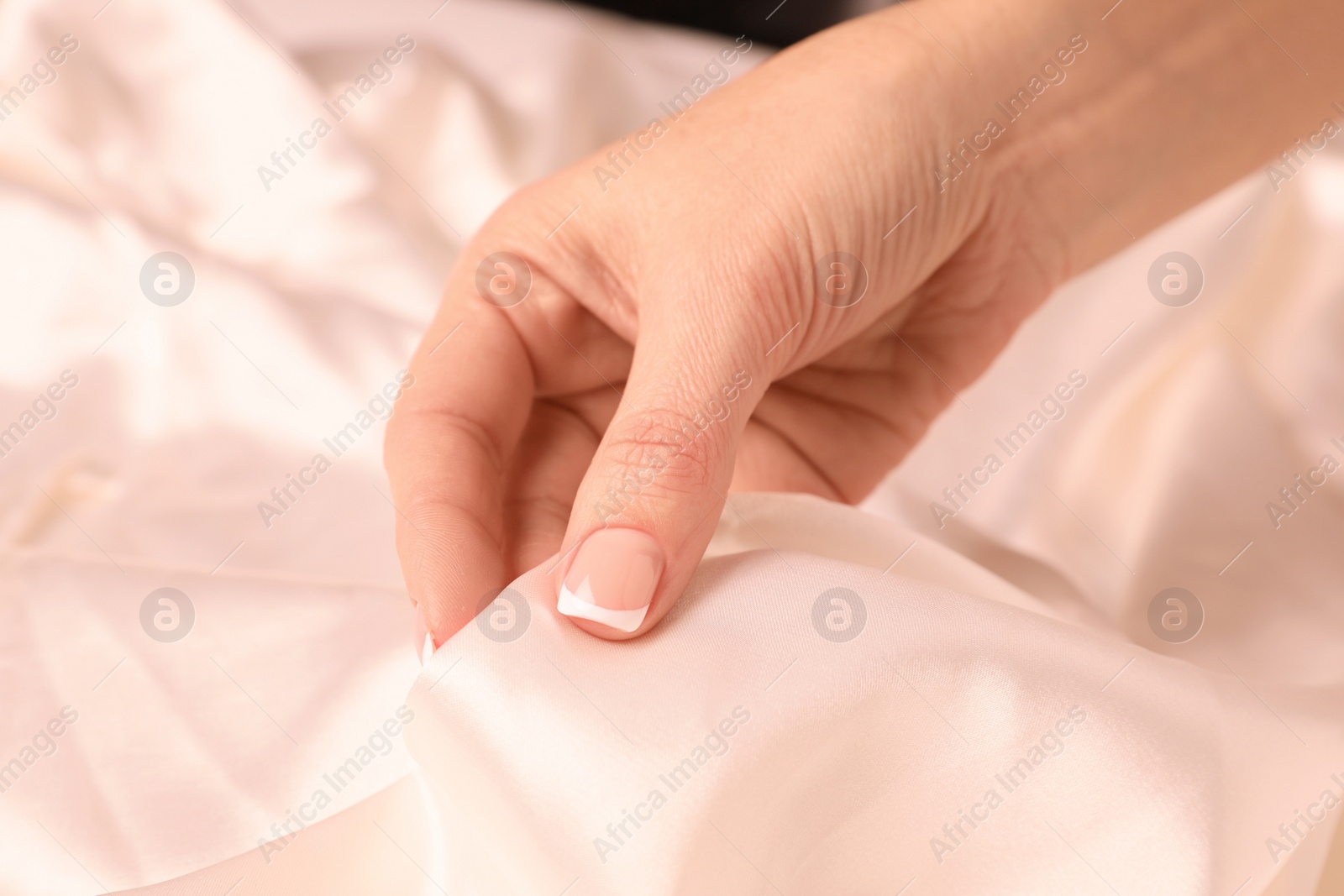 Photo of Woman touching smooth silky white fabric, closeup view