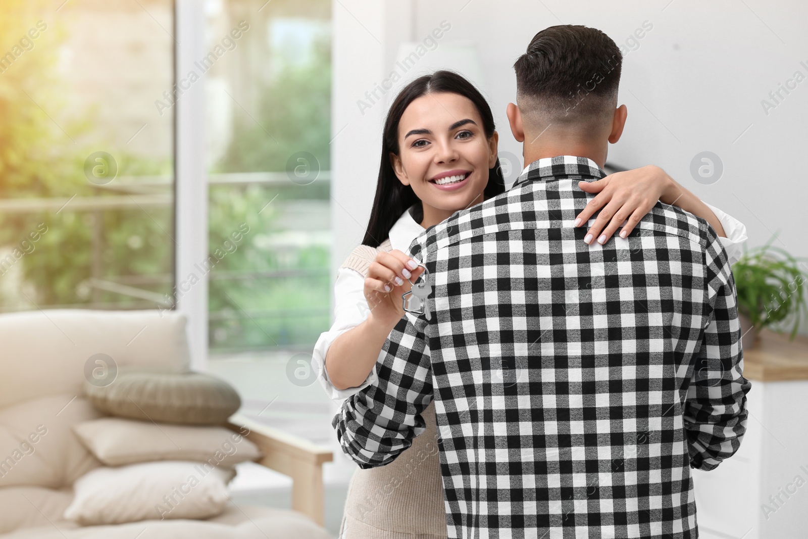 Photo of Happy couple with key from their new house indoors