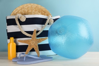 Photo of Light blue inflatable ball and different beach accessories on white wooden table