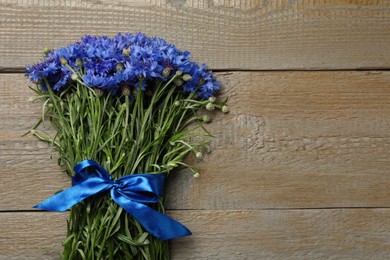 Photo of Bouquet of beautiful cornflowers on wooden table, top view. Space for text