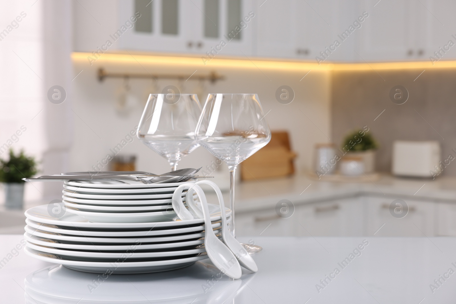 Photo of Set of clean dishware, glasses and cutlery on table in kitchen, space for text