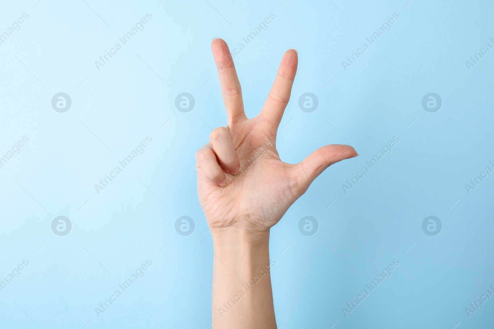 Photo of Woman showing number three on color background, closeup. Sign language