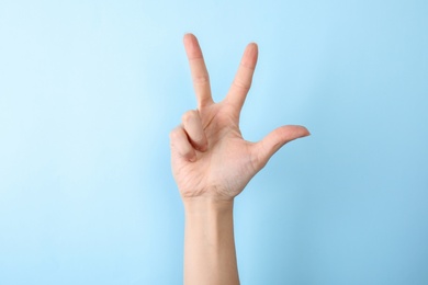 Photo of Woman showing number three on color background, closeup. Sign language