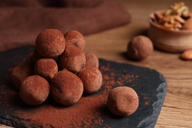 Photo of Tasty chocolate truffles powdered with cacao on slate board, closeup