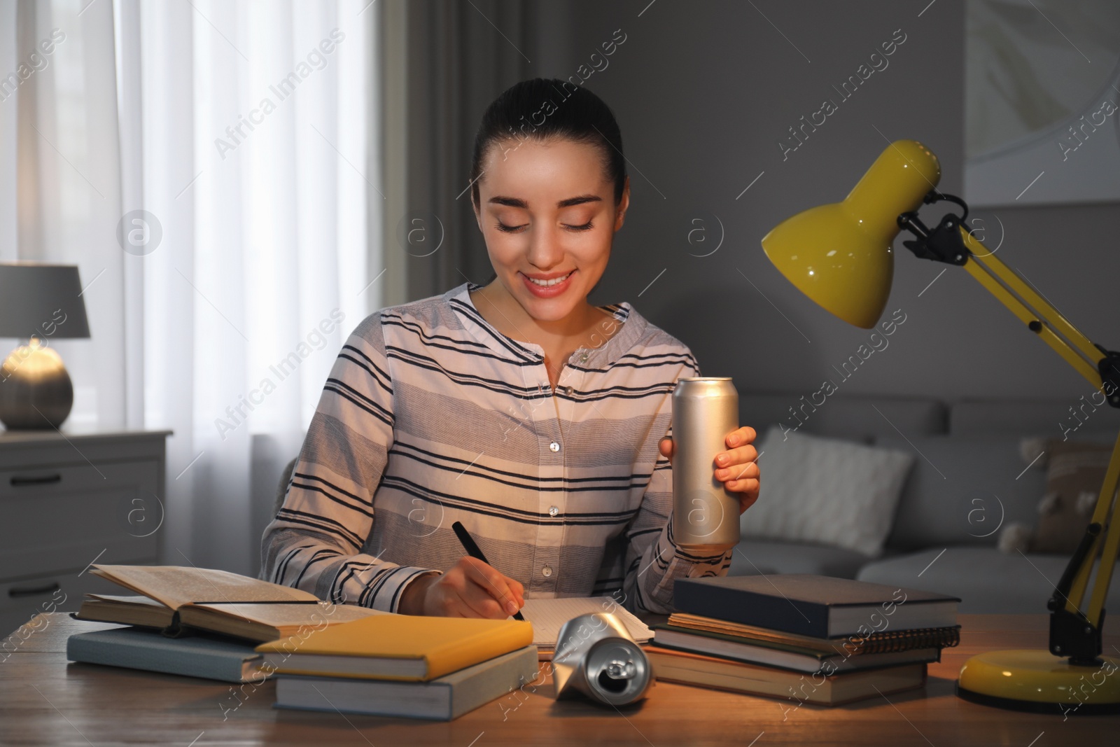 Photo of Young woman with energy drink studying at home