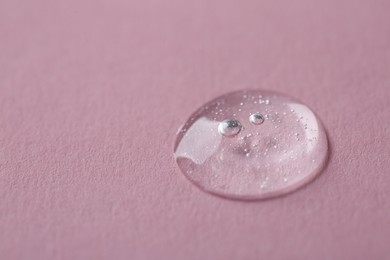 Photo of Drop of cosmetic serum on pink background, macro view. Space for text