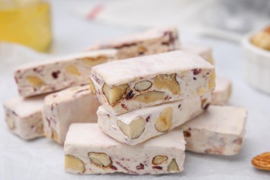 Photo of Pieces of delicious nutty nougat on white table, closeup