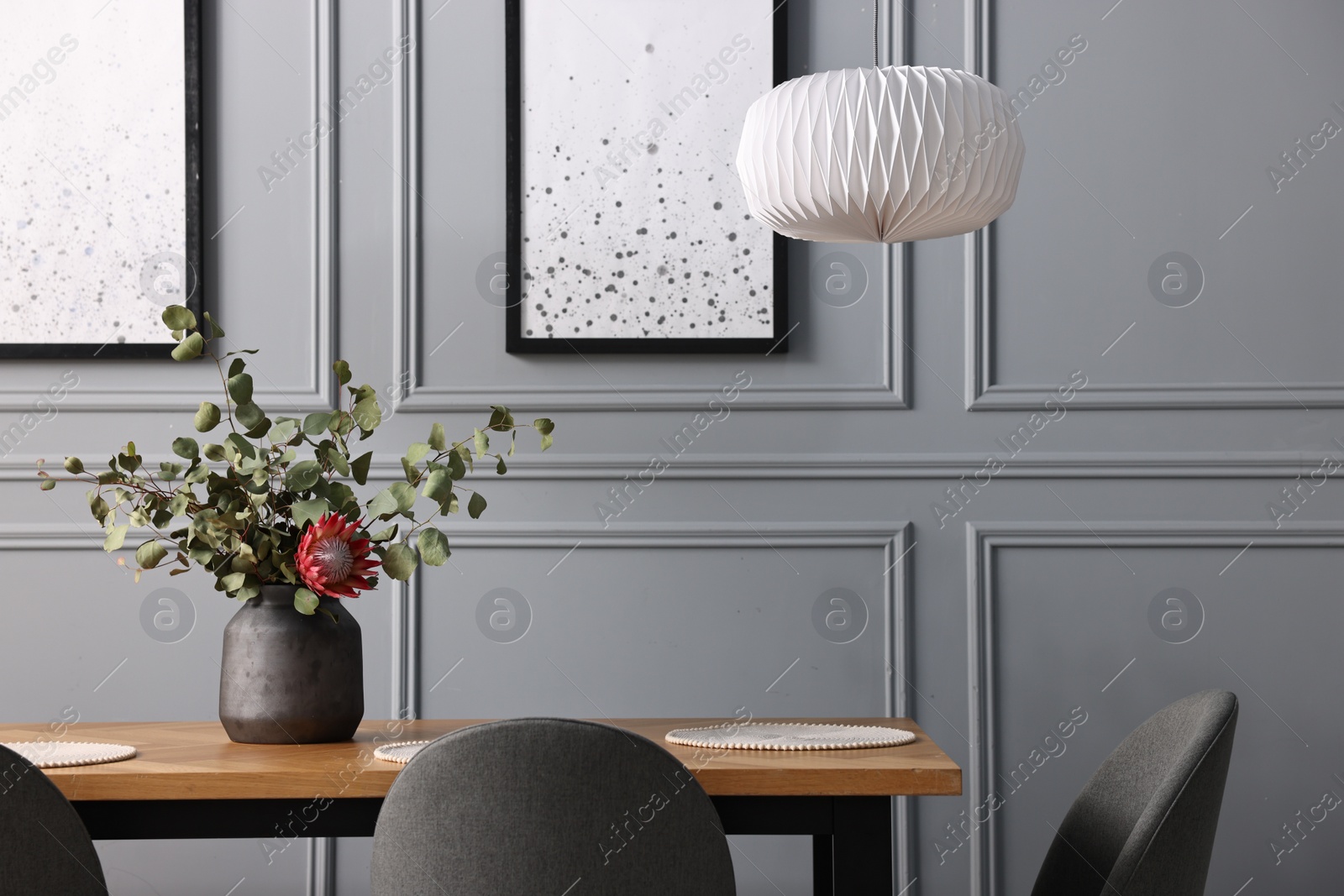 Photo of Soft chairs, table and vase with plants in stylish dining room