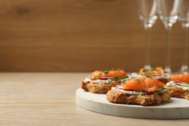 Tasty canapes with salmon, cucumber, radish and cream cheese on wooden table, space for text