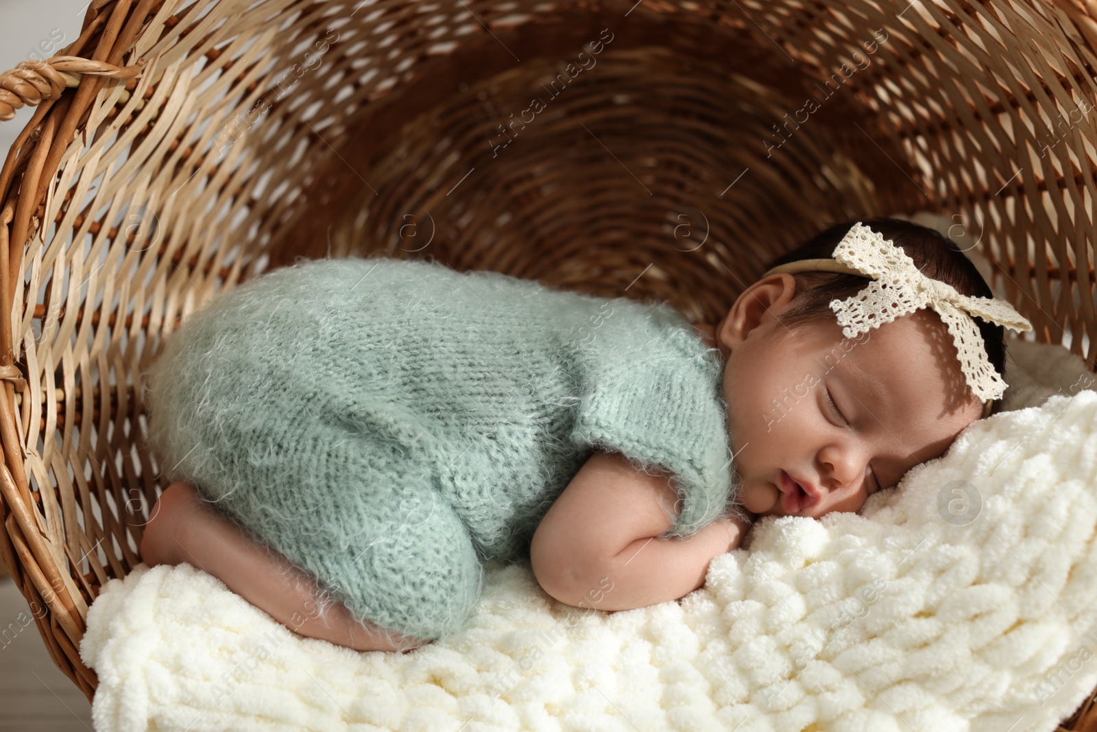 Photo of Adorable newborn baby sleeping in wicker basket with soft plaid