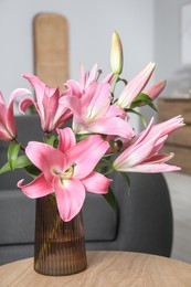 Photo of Beautiful pink lily flowers in vase on wooden table at home