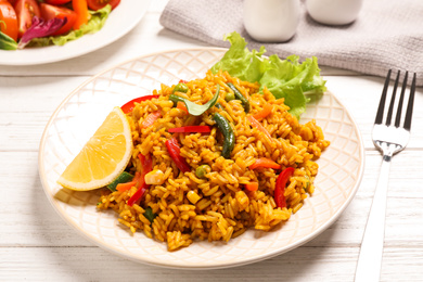Delicious rice pilaf with vegetables on white wooden table