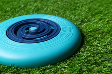 Photo of Light blue plastic frisbee disk on green grass, closeup