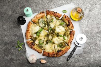 Photo of Delicious pizza with pesto, cheese and basil served on grey table, flat lay