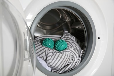 Photo of Green dryer balls and clothes in washing machine drum