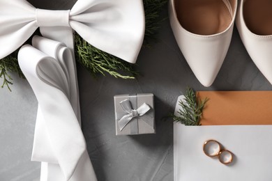 Flat lay composition with wedding rings, white high heel shoes and decor on grey background