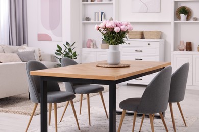 Photo of Stylish dining room with cosy furniture and flowers