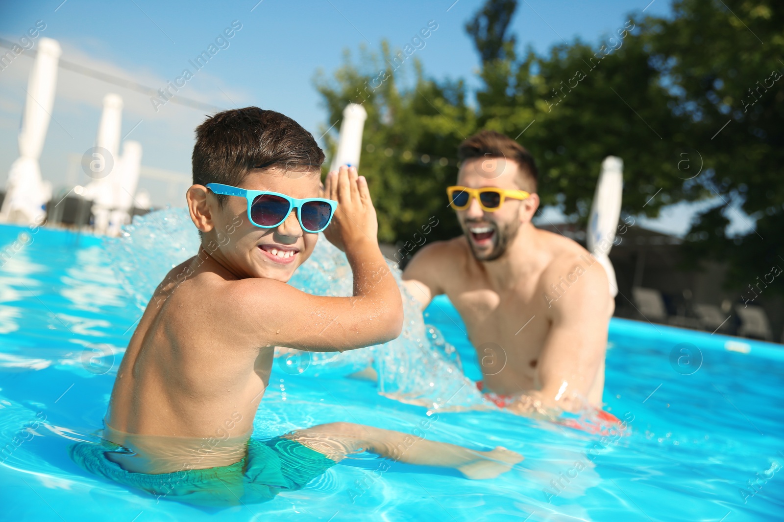 Photo of Father and son having fun in swimming pool. Family vacation