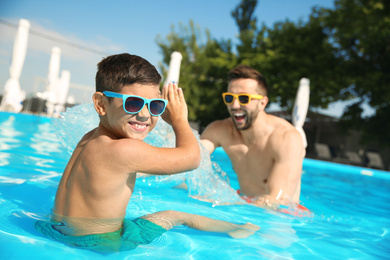 Father and son having fun in swimming pool. Family vacation