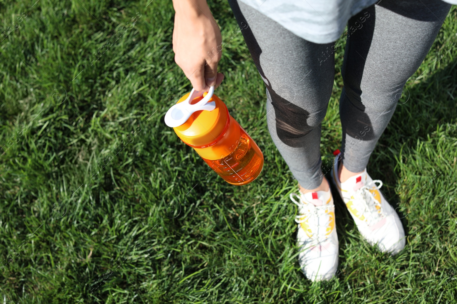 Photo of Young woman holding bottle with clean water outdoors. Space for text