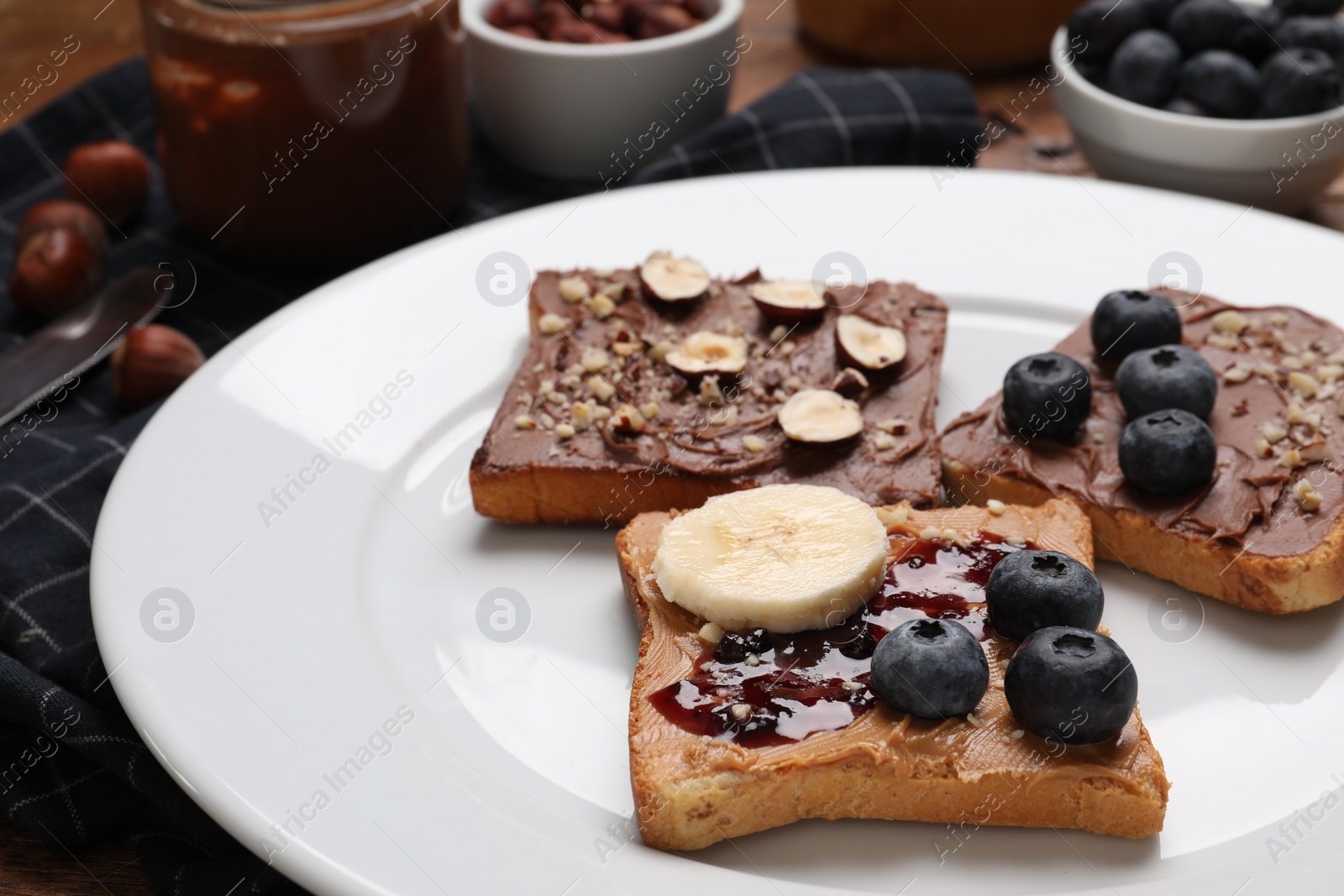 Photo of Different tasty toasts with nut butter and products on table, closeup