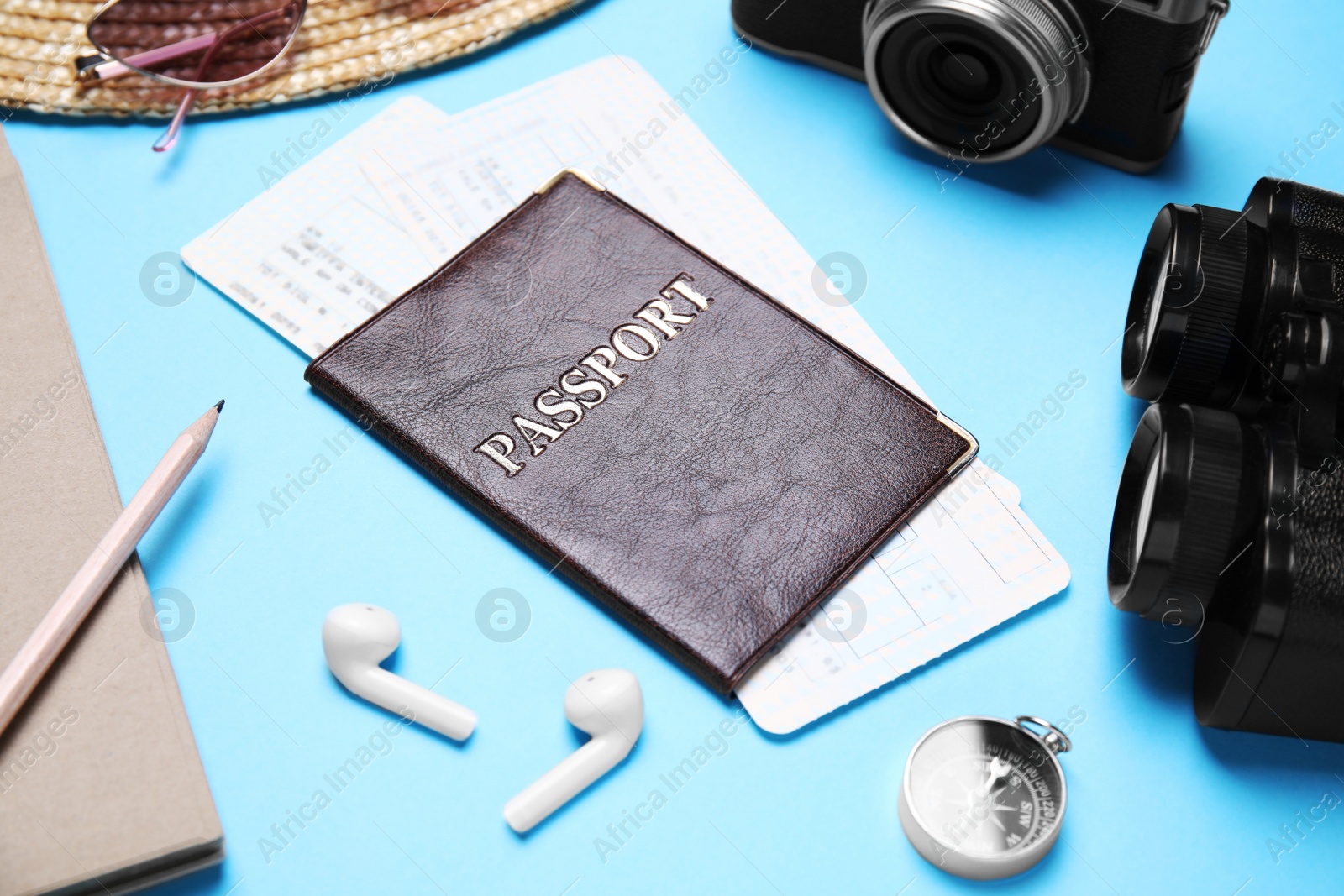 Photo of Passport with tickets among holiday items on light blue background